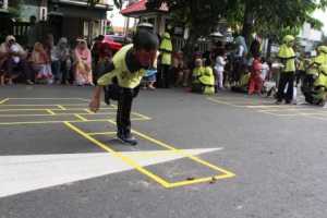 Salah satu siswa yang mukanya masih penuh riasan buto galak sedang mencoba permainan engklek atau sudamanda di acara “Sumringah Dolanan Bocah”.